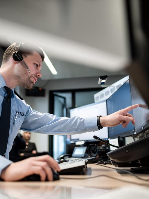Ein Polizist zeigt auf einen Monitor. Er stellt ein neues GPS-Monitoring bei der Polizei in Mönchengladbach vor. Der Einsatz der Streifenwagen soll damit besser gesteuert werden.