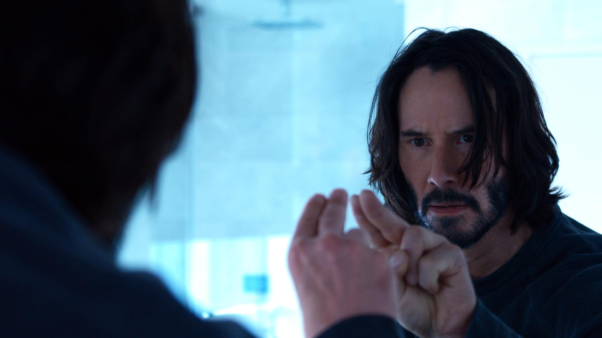 Keanu Reeves blickt in einer Aufnahme des neuen Matrix-Films in den Spiegel und berührt mit seinen Fingern sein Spiegelbild. Keanu Reeves blickt in einer Aufnahme des neuen Matrix-Films in den Spiegel und berührt mit seinen Fingern sein Spiegelbild.