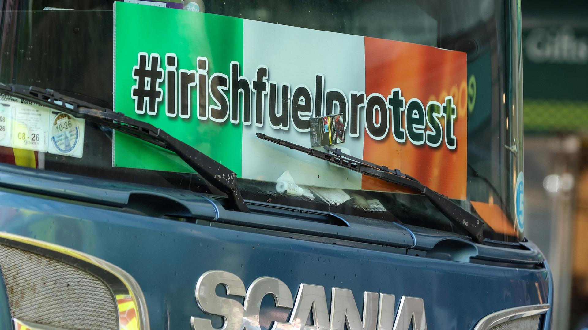 An der Frontscheibe ist ein Protest-Plakat mit der Aufschrift "Irischfuelprotest" angebracht.