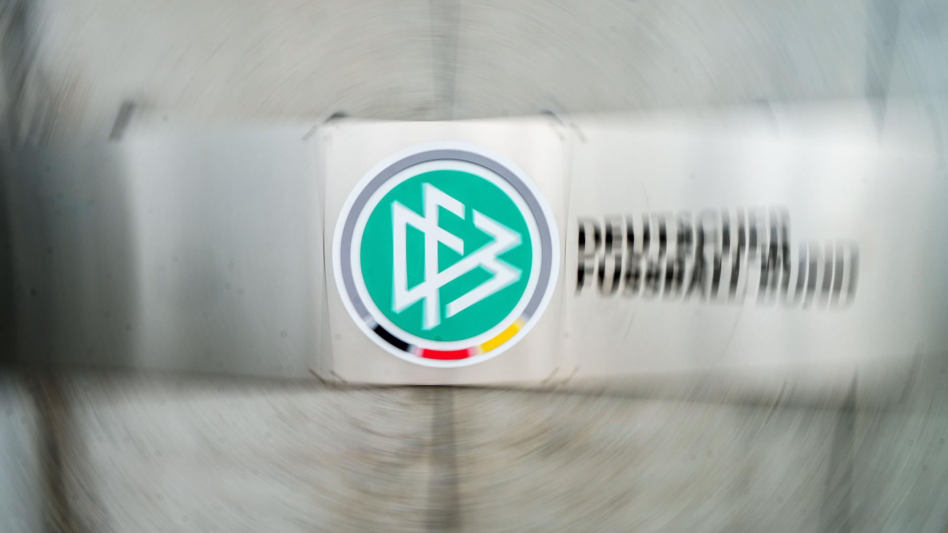 Ein Schild mit dem Logo des Deutschen Fußball-Bundes (DFB) hängt vor dem Eingang zur DFB-Zentrale (Aufnahme mit Dreheffekt). 