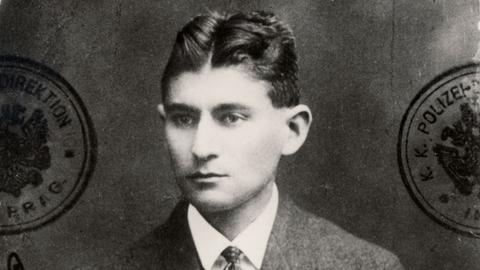 Ein schwarzweißes ausgefranstes Passfoto des jungen Schriftstellers Franz Kafka, der sehr ernst blickt Ein schwarzweißes ausgefranstes Passfoto des jungen Schriftstellers Franz Kafka, der sehr ernst blickt