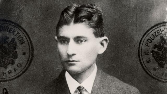 Ein schwarzweißes ausgefranstes Passfoto des jungen Schriftstellers Franz Kafka, der sehr ernst blickt