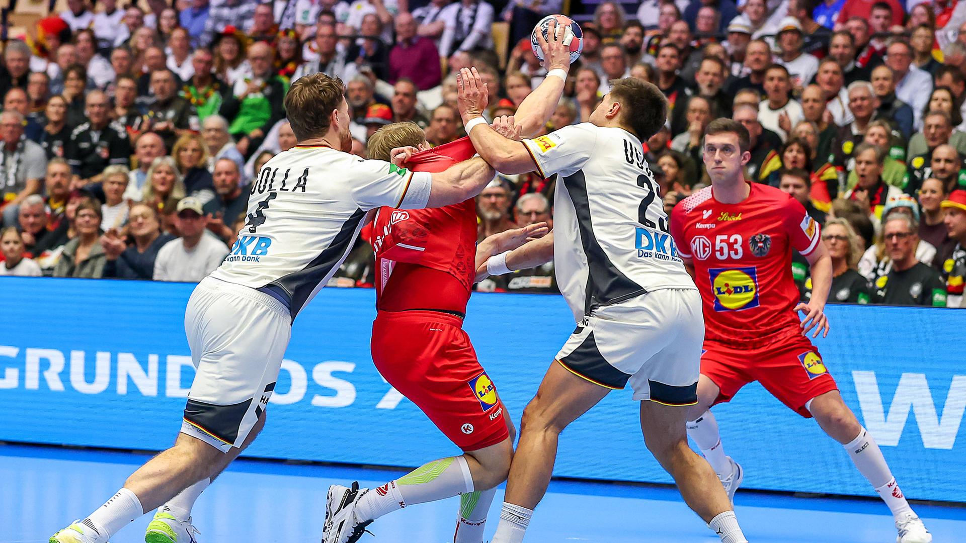 Auftakt der Handball-EM: Deutschland spielt gegen Östereich. Spieler beider Mannschaften kämpfen um den Ball.