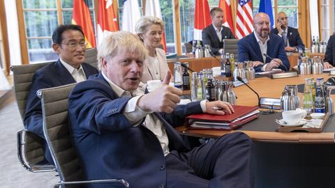 Premier Boris Johnson sitzt an einem Tisch mit anderen Politikern beim G7-Treffen und hält seinen Daume hoch.