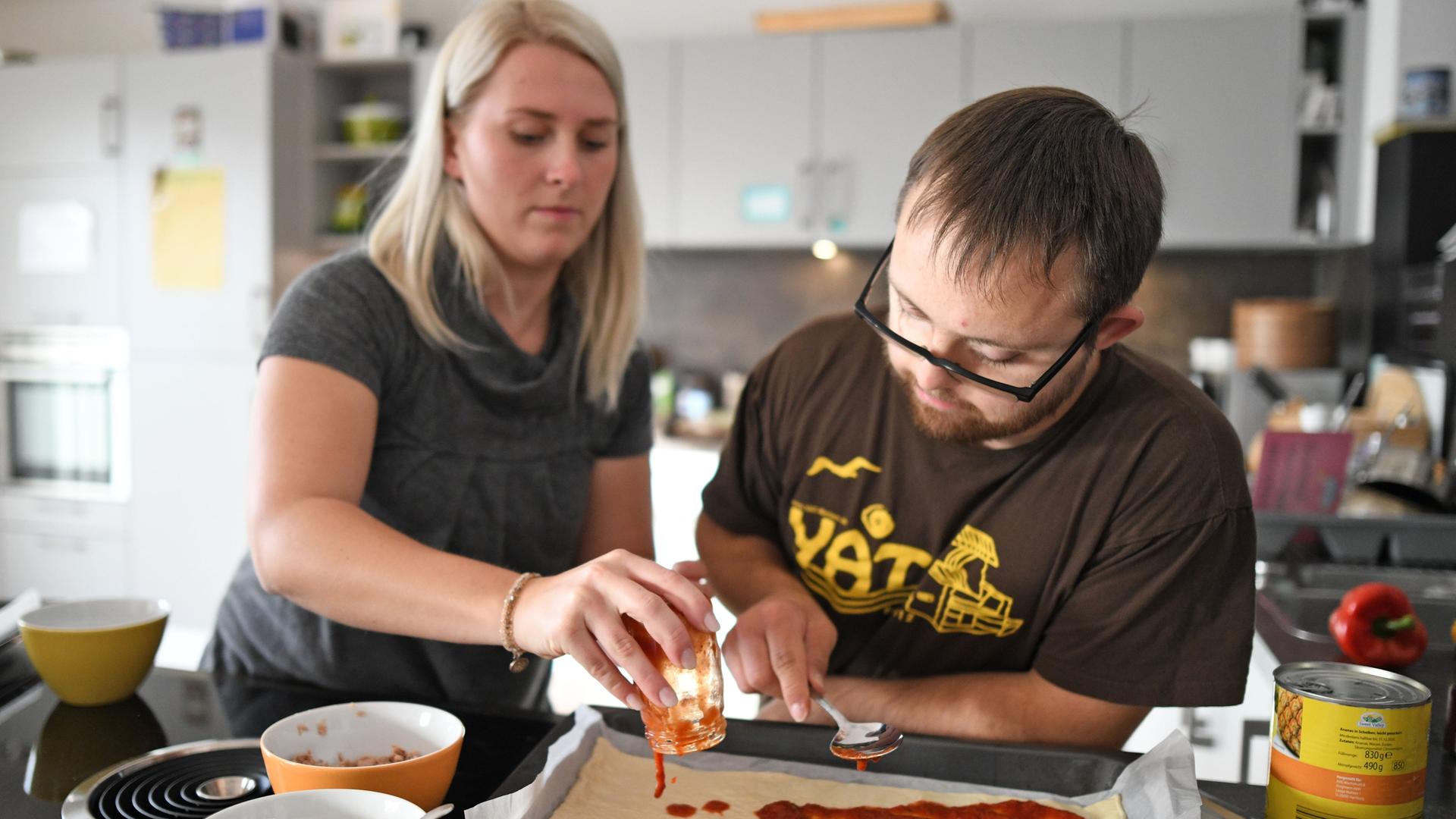 Bewohner einer Wohn-Gemeinschaft aus Studierenden und Menschen mit Behinderung bereiten eine Pizza vor