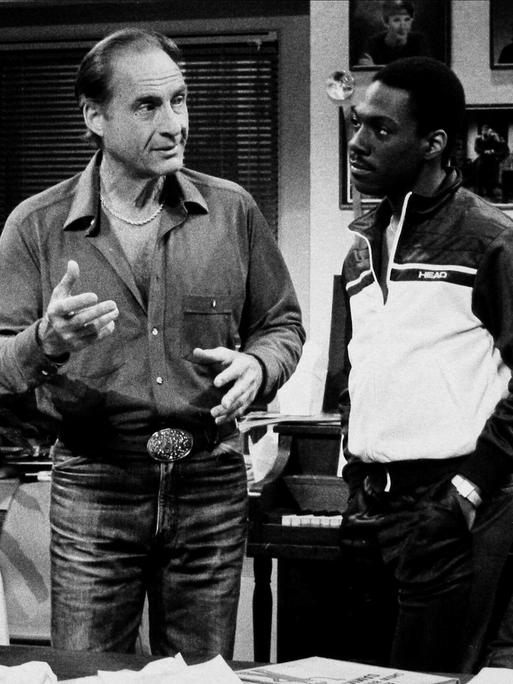 Ein Schwarz-Weiß-Foto zeigt die US-Komiker Julia Louis Dreyfus, Sid Caesar und Eddie Murphy (v. l.n.r.) in einer Ausgabe von „Saturday Night Live“ im Jahr 1983.