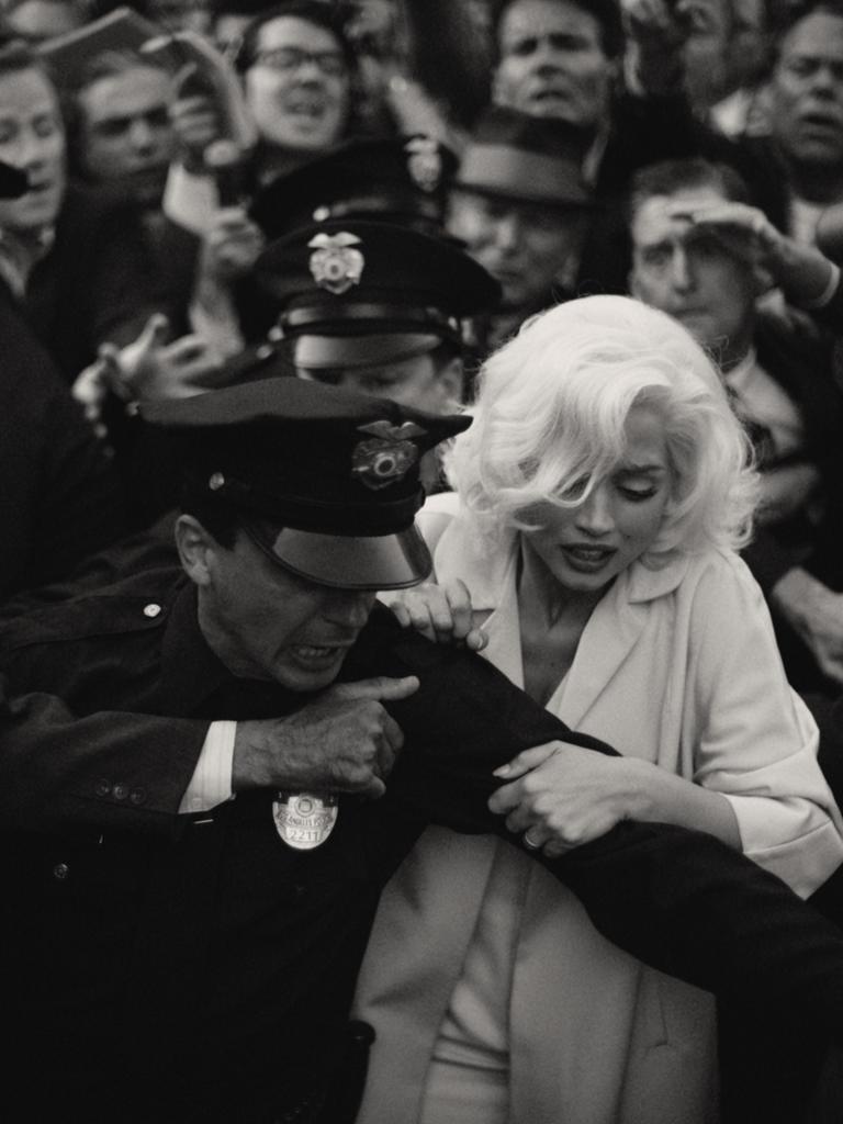 Die Filmszene in Schwarz-Weiß zeigt, wie Marilyn Monroe von einem Polizisten abgeführt wird.