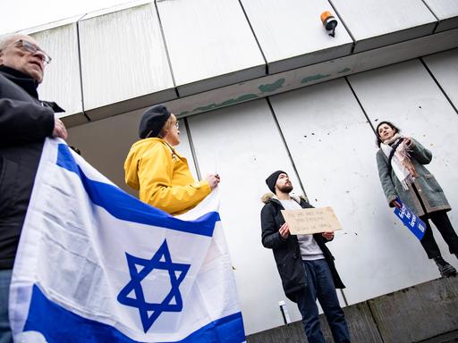 Aufnahme von schräg unten. Links eine Person, die eine Israel-Flagge hält. 
