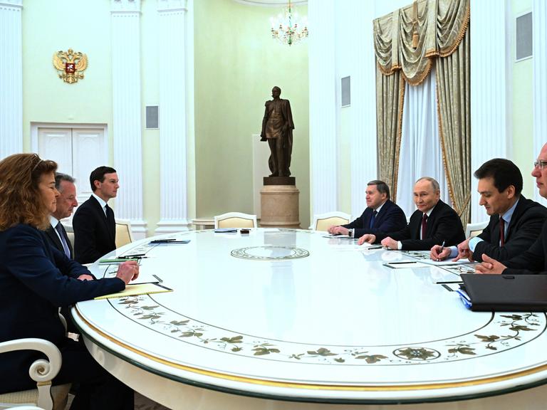 An einem großen weißen Tisch sitzen u.a. Russlands Präsident Wladimir Putin und die US-Sondergesandten Steve Witkoff und Jared Kushner