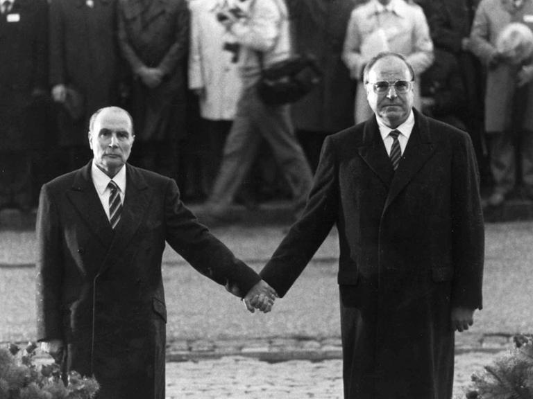 Der frühere französische Präsident Francois Mitterrand und der deutsche Bundeskanzler Helmut Kohl stehen bei einer Feier zur deutsch-französischen Versöhnung am Friedhof Douaumont in der Nähe von Verdun