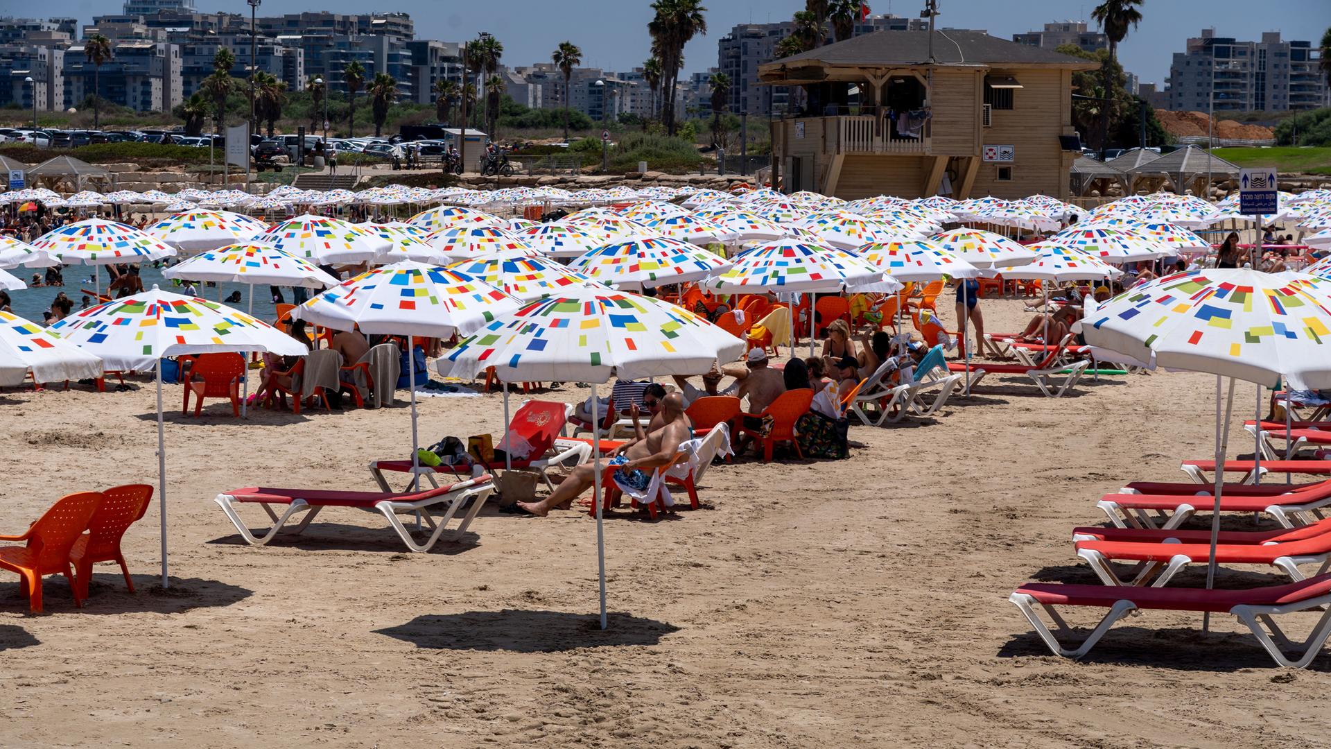 Strandleben in Tel Aviv mit Liegestühlen und Sonnenschirmen. 