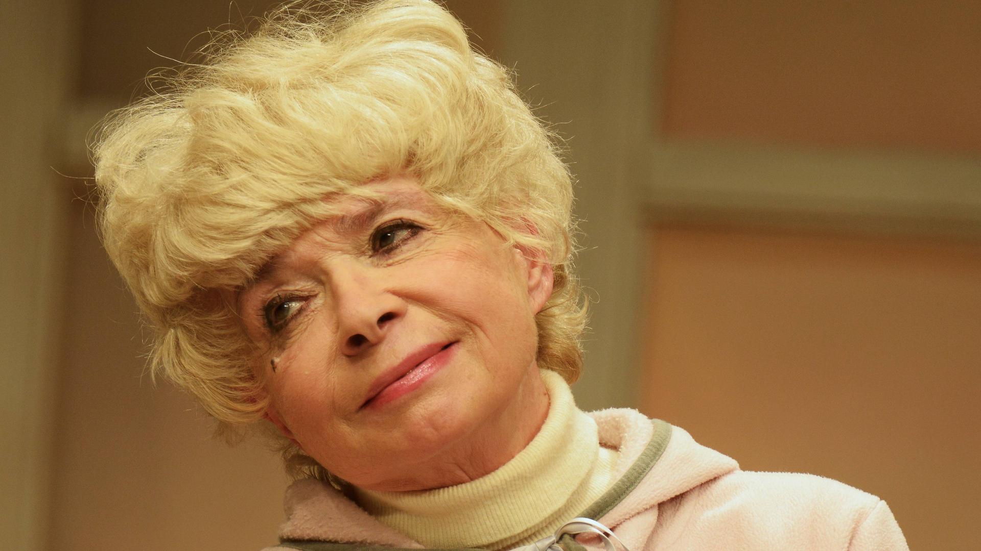 Ingrid Steeger im Jahr 2015 in der Komödie "Der Kurschattenmann" im Winterhuder Fährhaus" in Hamburg. Sie trägt einen Rollkragenpullover und darüber einen Kapuzenpulli; sie lächelt und hält den Kopf leicht schräg.