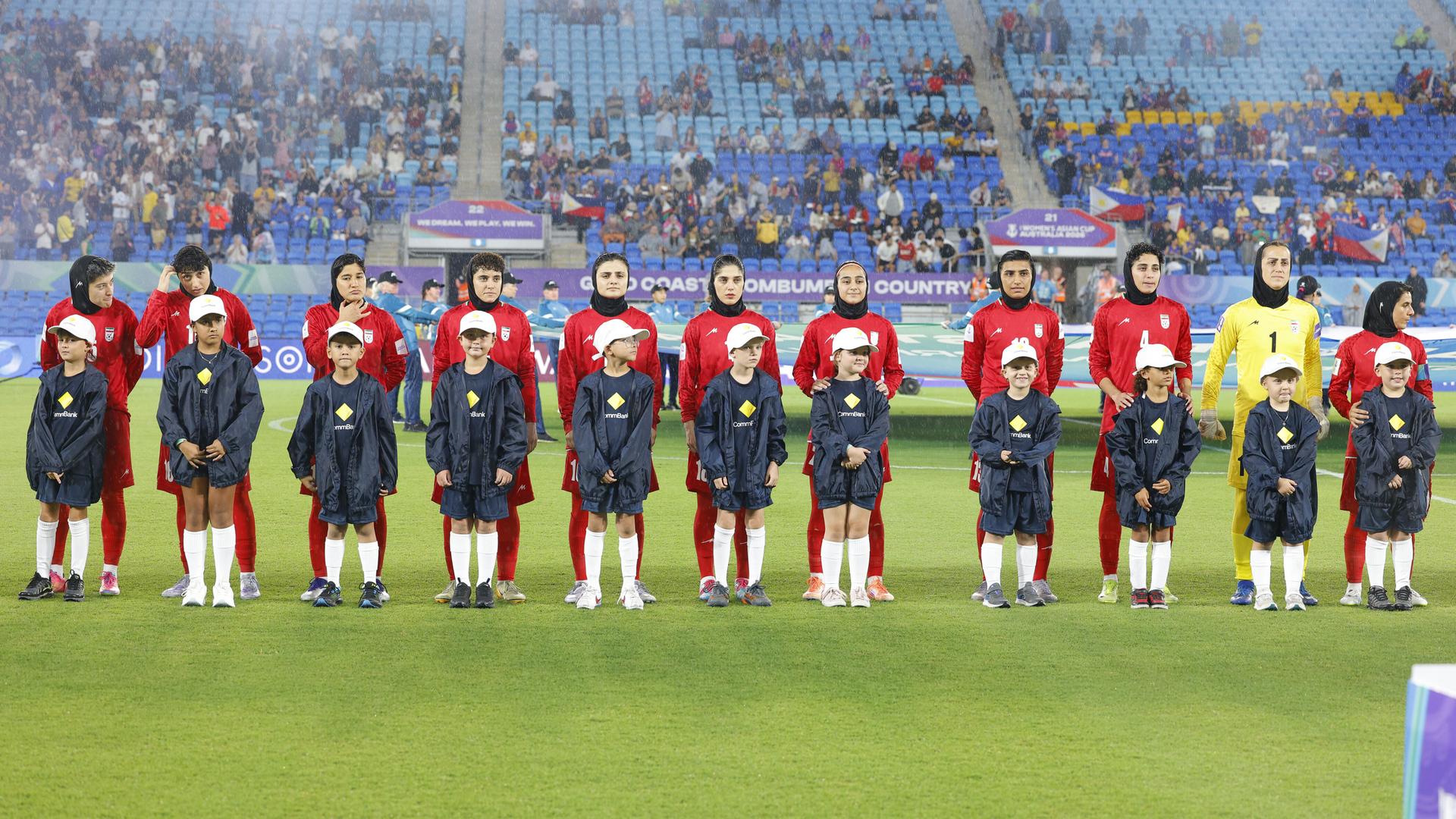 Die Spielerinnen der iranischen Nationalmannschaft stehen aufgereiht vor dem Spiel auf dem Feld.