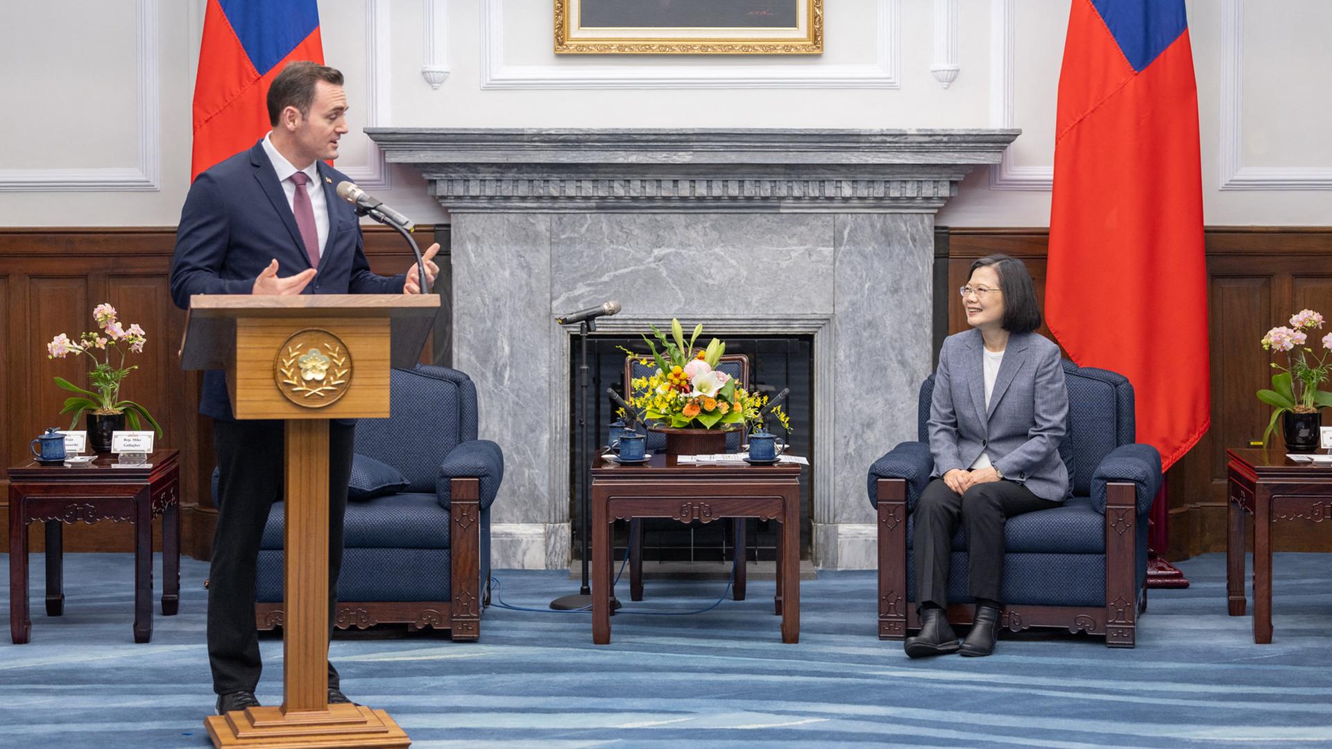 Der republikanische US-Abgeordnete Mike Gallagher steht hinter einem Rednerpult. Seitlich von ihm sitzt die Präsident Taiwans, Tsai Ing-wen auf einem Stuhl. Der republikanische US-Abgeordnete Mike Gallagher steht hinter einem Rednerpult. Seitlich von ihm sitzt die Präsident Taiwans, Tsai Ing-wen auf einem Stuhl.