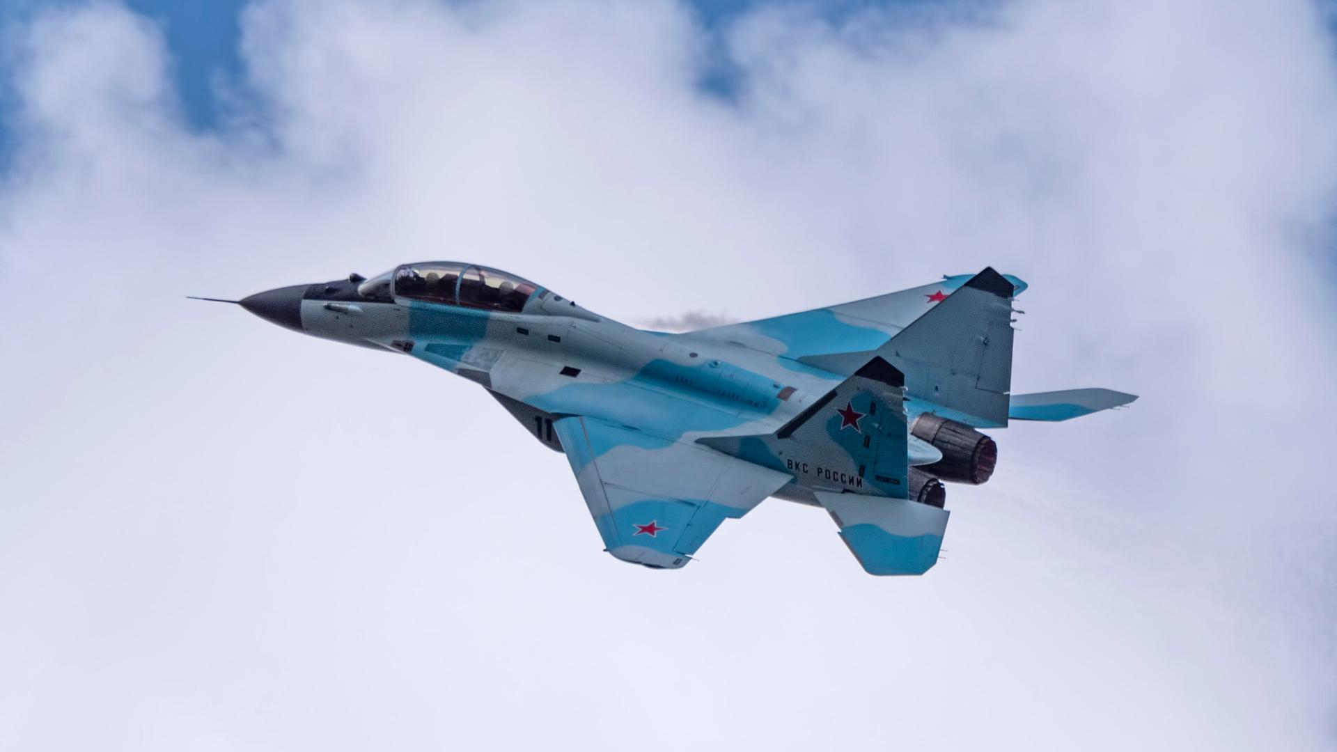 Russischer Kampfjet fliegt vor weißen Wolken am Himmel