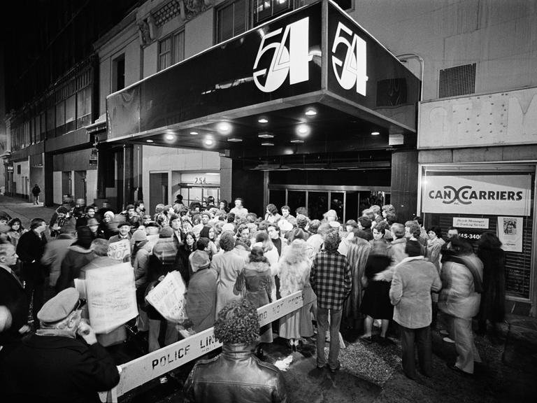 Ein Club mit der Aufschrift Studio 54, davor eine Menschenmenge.