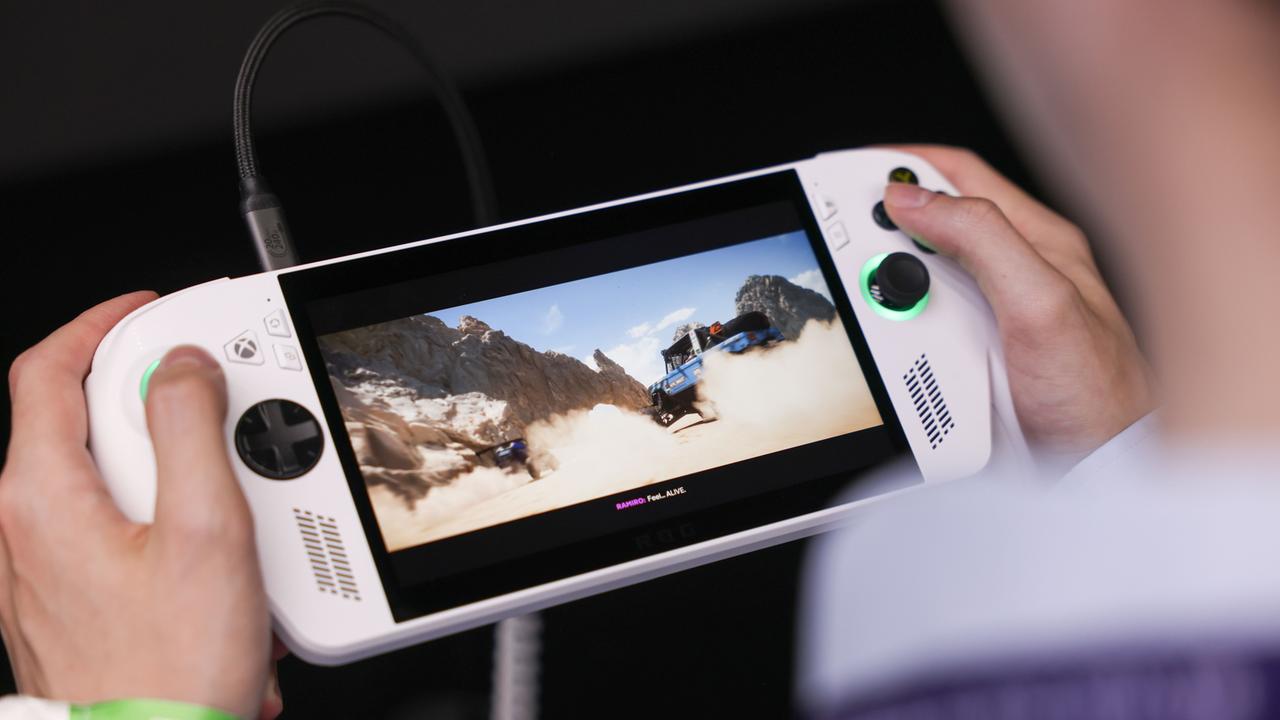 Zwei Hände halten die Konsole, auf deren Display man ein Spiel sieht.  