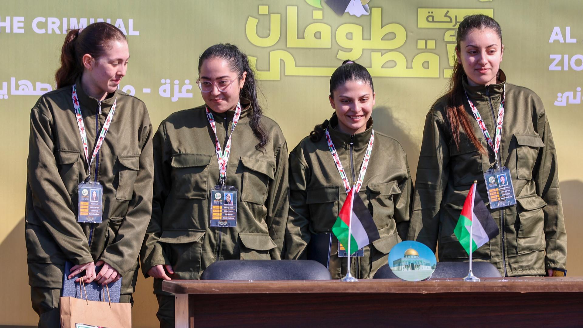 Die vier israelischen Geiseln Naama Levy, Karina Ariev, Liri Albag und Daniella Gilboa stehen auf einer Bühne im Gazastreifen, bevor Hamas-Kämpfer sie an das Rote Kreuz übergeben.