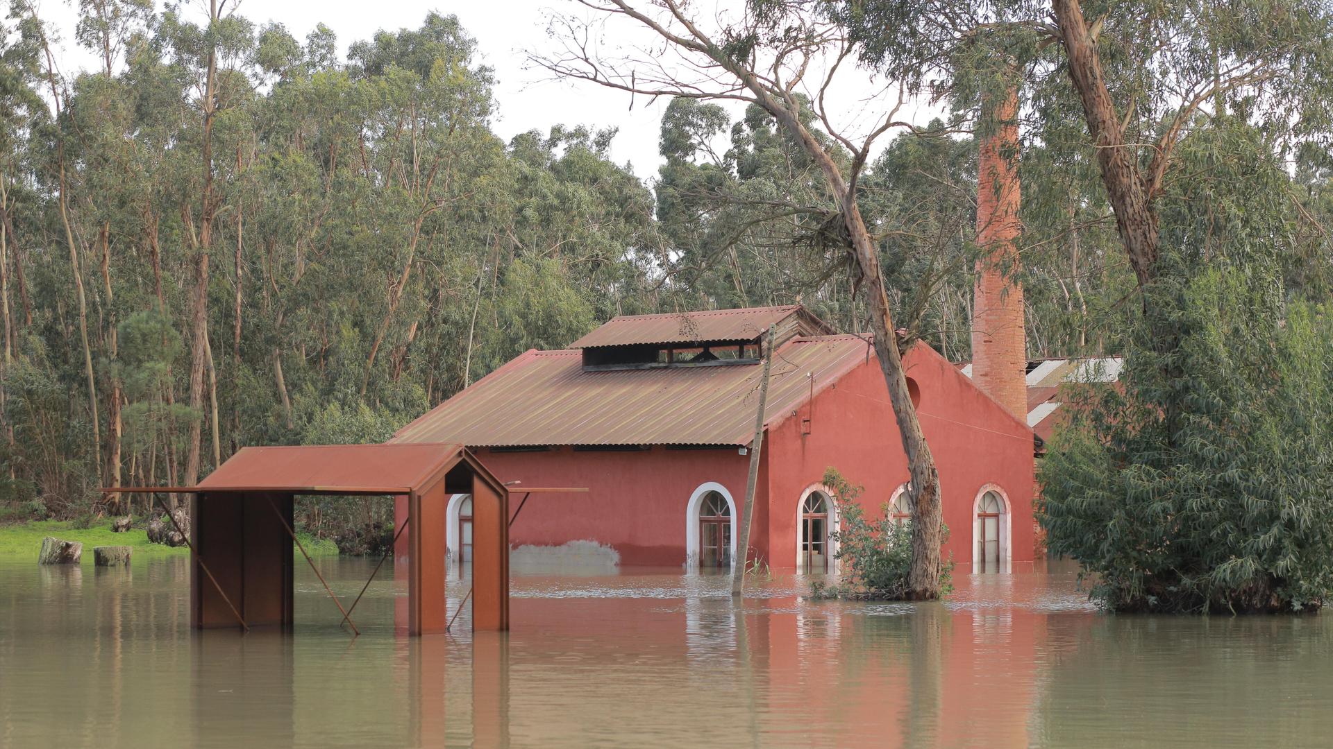 Ein rotes Gebäude steht bis hoch zu den Fenstern im schlammigen Wasser.