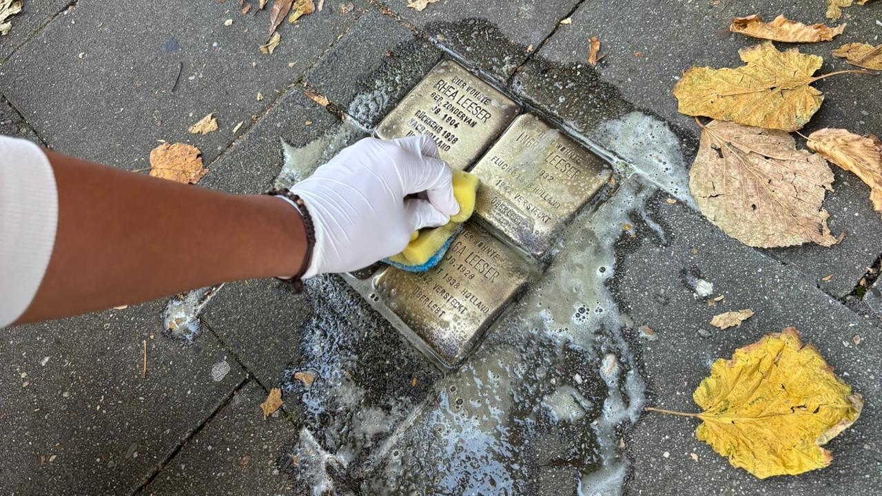 Das Foto zeigt eine Person, die einen Stolperstein putzt. Das Foto zeigt eine Person, die einen Stolperstein putzt.