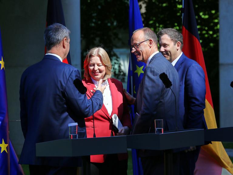 Bayerns Ministerpräsident Markus Söder (CSU), Arbeitsministerin Bärbel Bas (SPD), Bundeskanzler Friedrich Merz (CDU), Finanzminister Lars Klingbeil (SPD) schütteln sich nach einer Pressekonferenz die Hand und lächeln. 