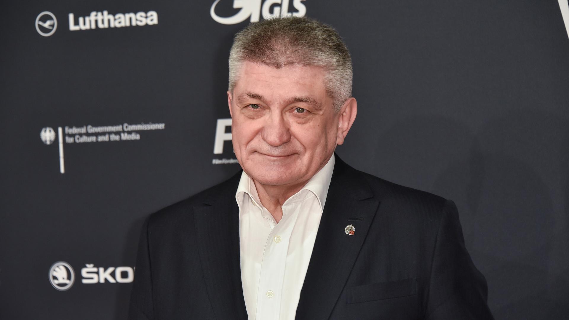 Der Filmemacher Alexander Sokurow steht vor einer Werbewand und guckt in die Kamera Der Filmemacher Alexander Sokurow steht vor einer Werbewand und guckt in die Kamera