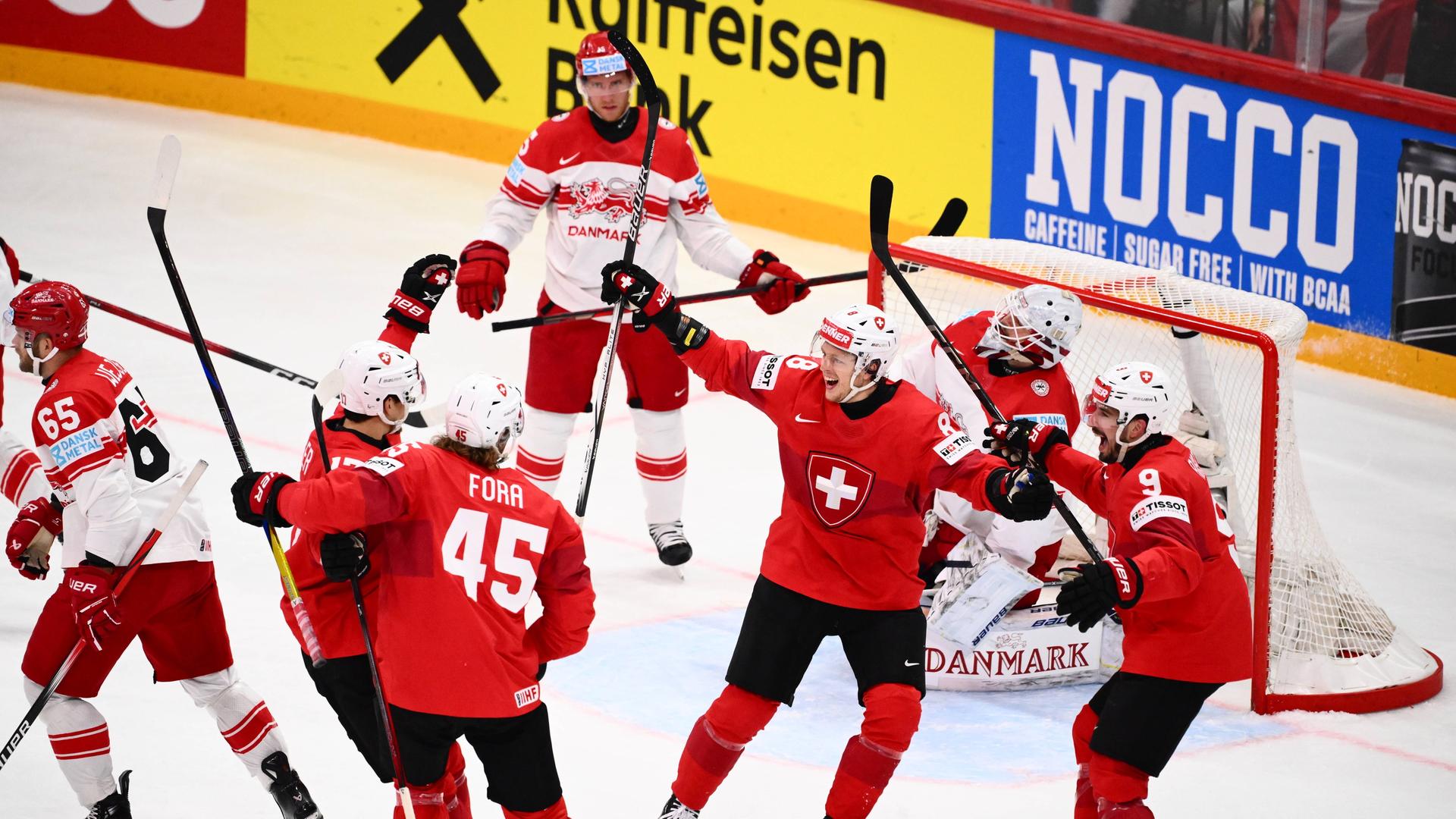 Mehrere Schweizer Eishockey-Spieler in roten Trikots jubeln nach einem Tor gegen Dänemark.
