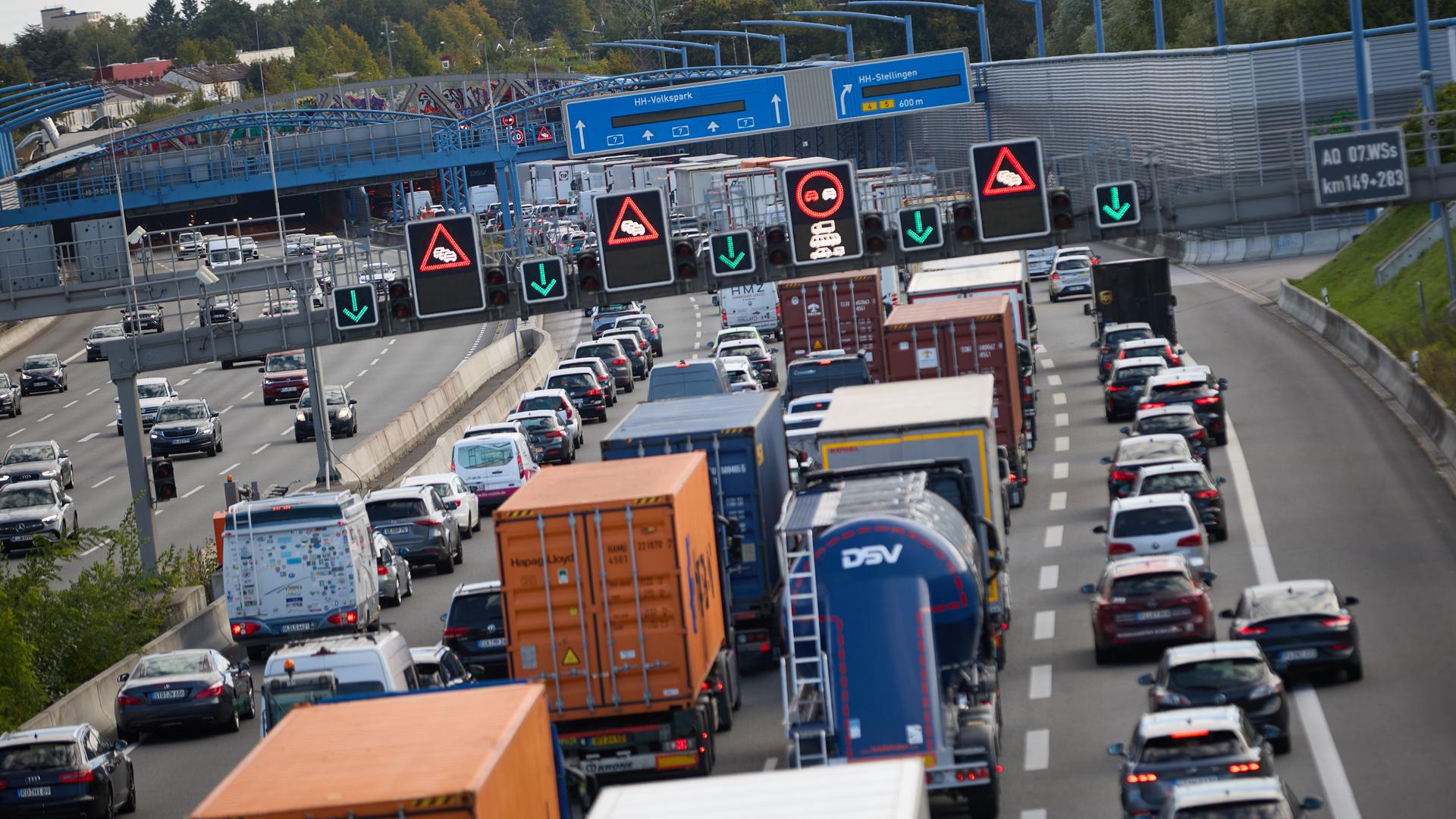Die rechte Fahrbahn ist voller Autos im Stau, die man von hinten sieht. Auf der linken Fahrbahn läuft der Verkehr. Im Bildhintergrund die Ein- und Ausfahrten des Tunnels. 