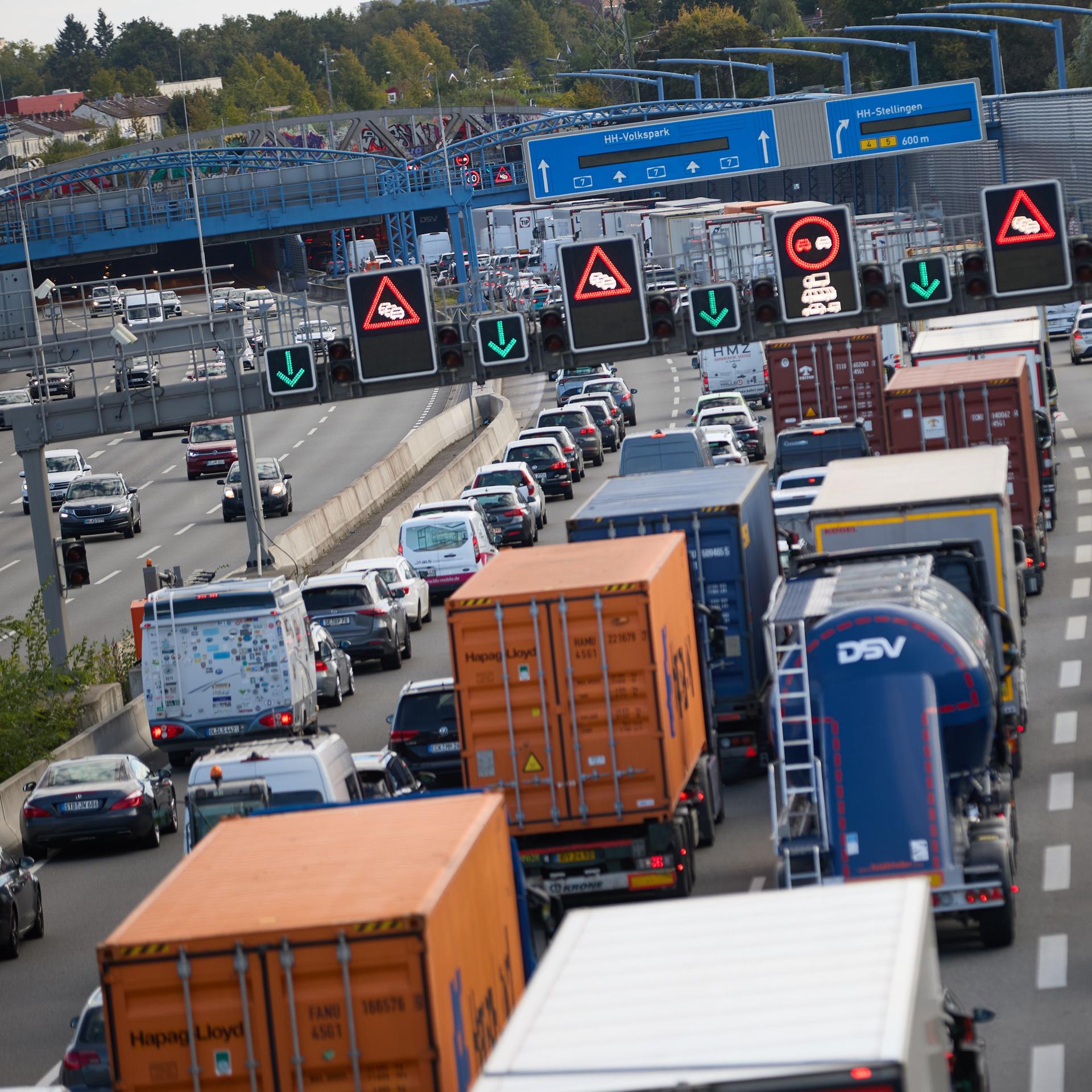 Die rechte Fahrbahn ist voller Autos im Stau, die man von hinten sieht. Auf der linken Fahrbahn läuft der Verkehr. Im Bildhintergrund die Ein- und Ausfahrten des Tunnels. 