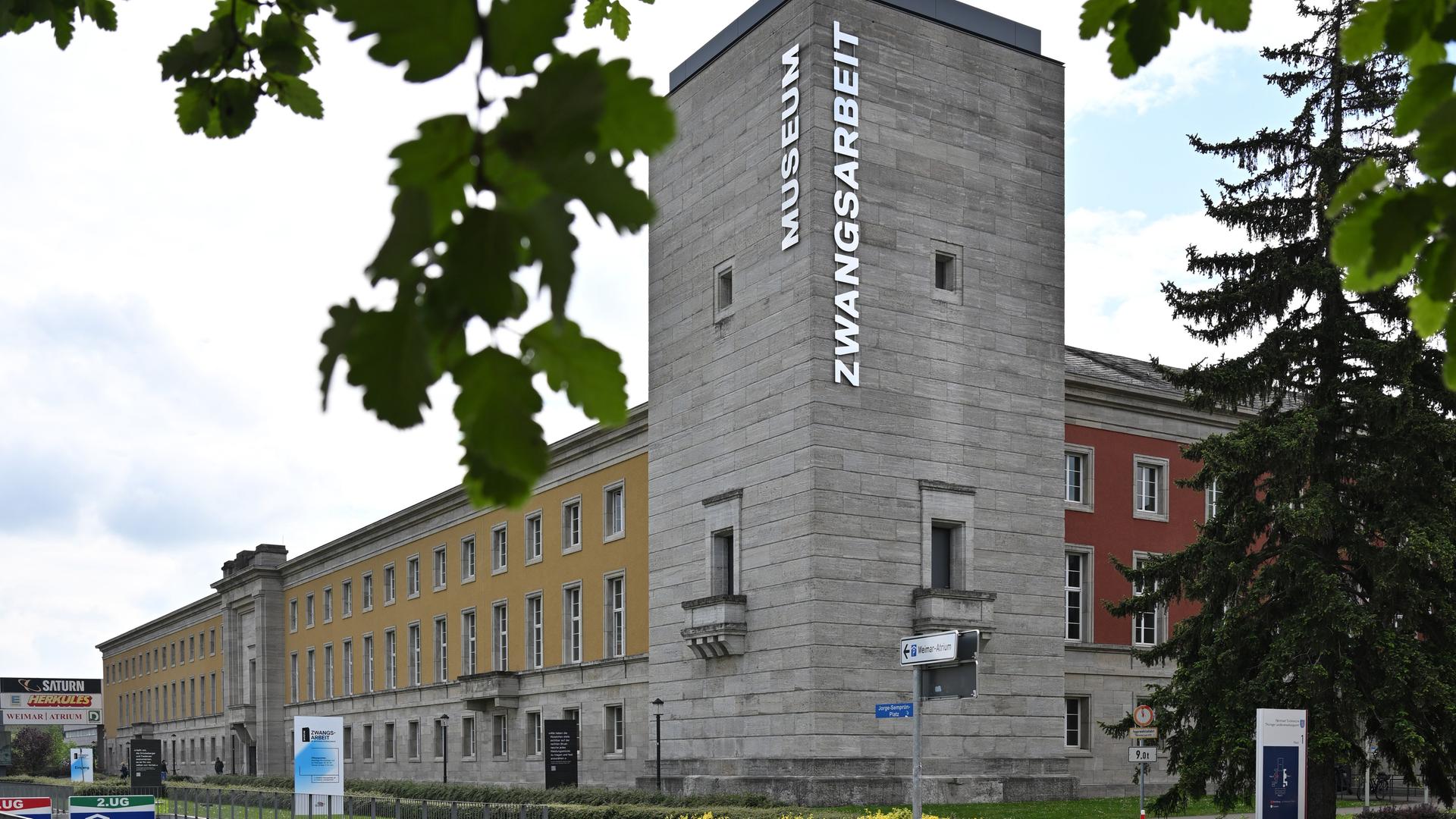 Ein langes Haus mit einem kleinen, rechteckigen Turm ist zu sehen. Auf dem Turm steht "Museum Zwangsarbeit".