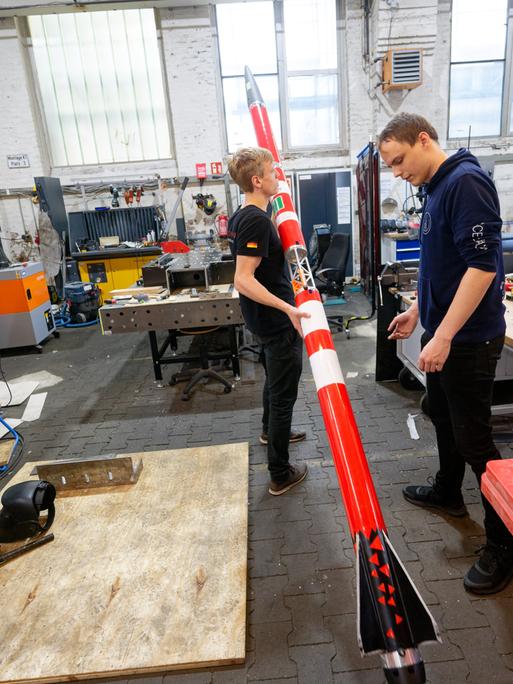 Die Studenten Florian Schuler (l) und Johann Schepke vom Space Team Aachen stehen mit ihrer Rakete in der Werkstatt. Der Flugkörper soll mit zweifacher Schallgeschwindigkeit von einem Schiff von der Nordsee aus starten.