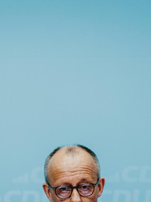 Die obere Hälfte von Friedrich Merz' Kopf am untern Bildrand vor dem grünblauen Hintergrund einer Wand Die obere Hälfte von Friedrich Merz' Kopf am untern Bildrand vor dem grünblauen Hintergrund einer Wand