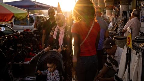 Gegenlichtaufnahme: Menschen gehen über eine Straße am Rande des Markts rund um die Medina in Casablanca