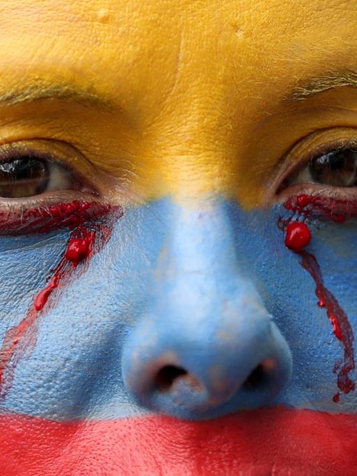 Eine regierungskritische Demonstrantin, deren Gesicht mit den Farben der kolumbianischen Nationalflagge bemalt ist, bei einem Protest in Bogota, Kolumbien