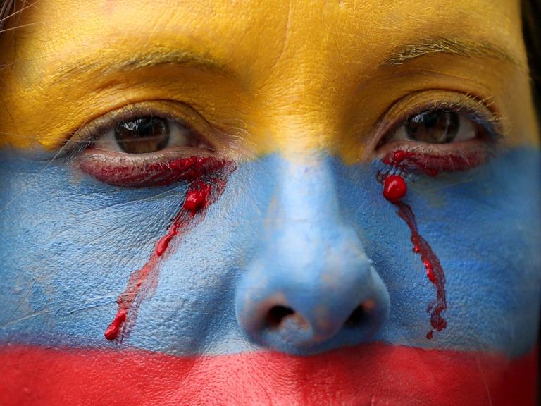 Eine regierungskritische Demonstrantin, deren Gesicht mit den Farben der kolumbianischen Nationalflagge bemalt ist, bei einem Protest in Bogota, Kolumbien