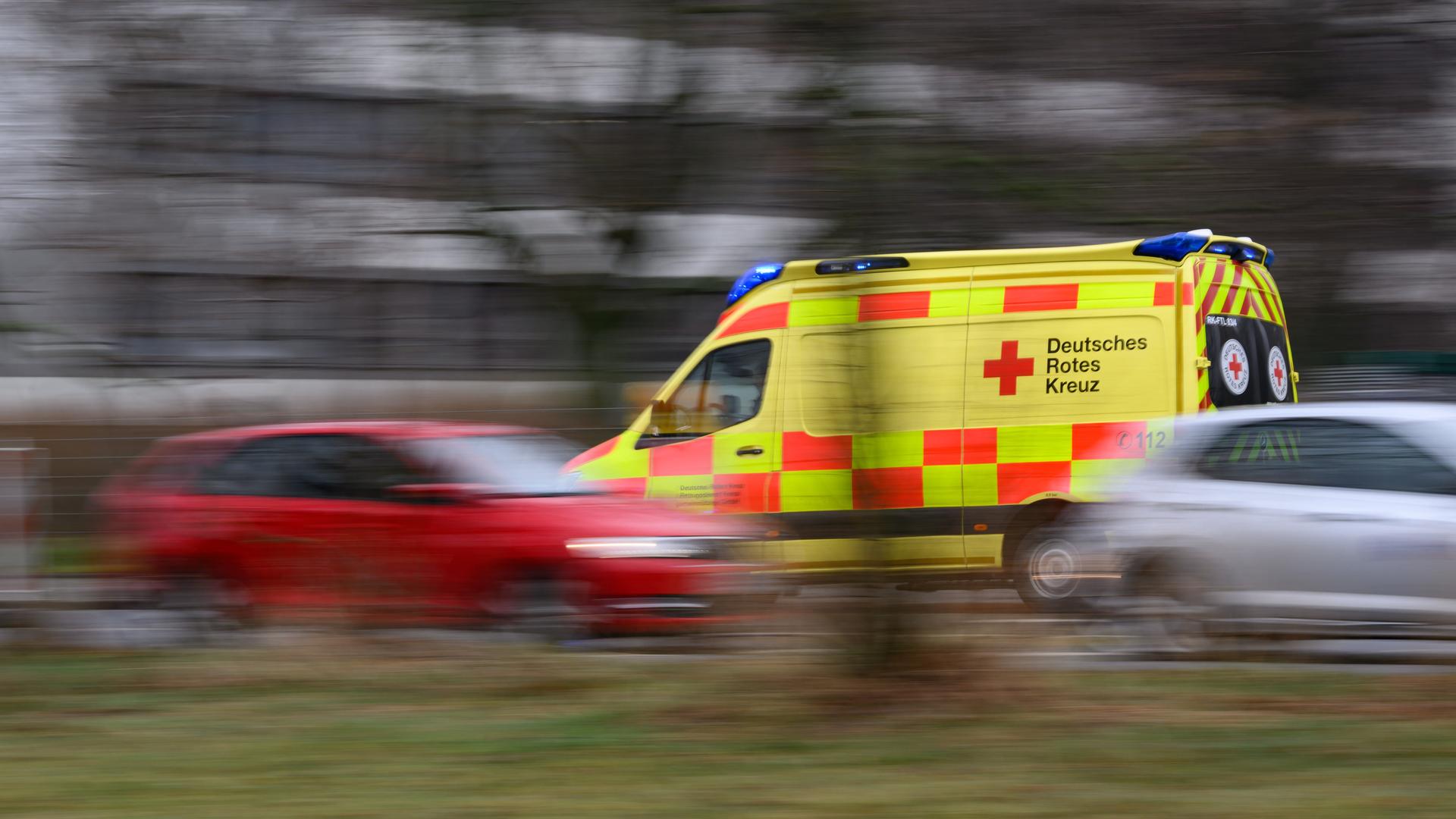 Ein Auto vom Rettungsdienst des DRK Freital fährt mit Blaulicht am Terrassenufer entlang. Es ist eine Aufnahme mit langer Belichtungszeit, die fahrenden Autos sind verschwommen, was die Hektik der Situation unterstreicht.