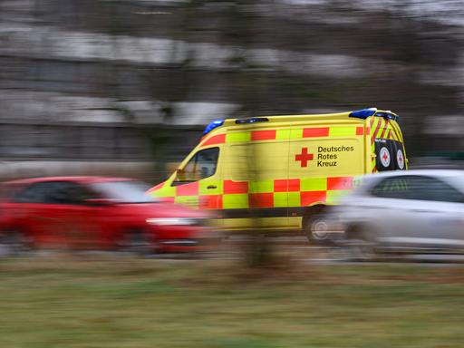 Ein Auto vom Rettungsdienst des DRK Freital fährt mit Blaulicht am Terrassenufer entlang. Es ist eine Aufnahme mit langer Belichtungszeit, die fahrenden Autos sind verschwommen, was die Hektik der Situation unterstreicht.