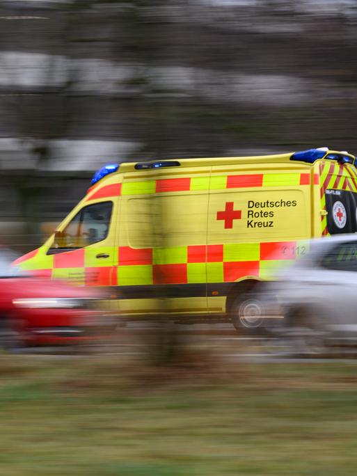 Ein Auto vom Rettungsdienst des DRK Freital fährt mit Blaulicht am Terrassenufer entlang. Es ist eine Aufnahme mit langer Belichtungszeit, die fahrenden Autos sind verschwommen, was die Hektik der Situation unterstreicht.