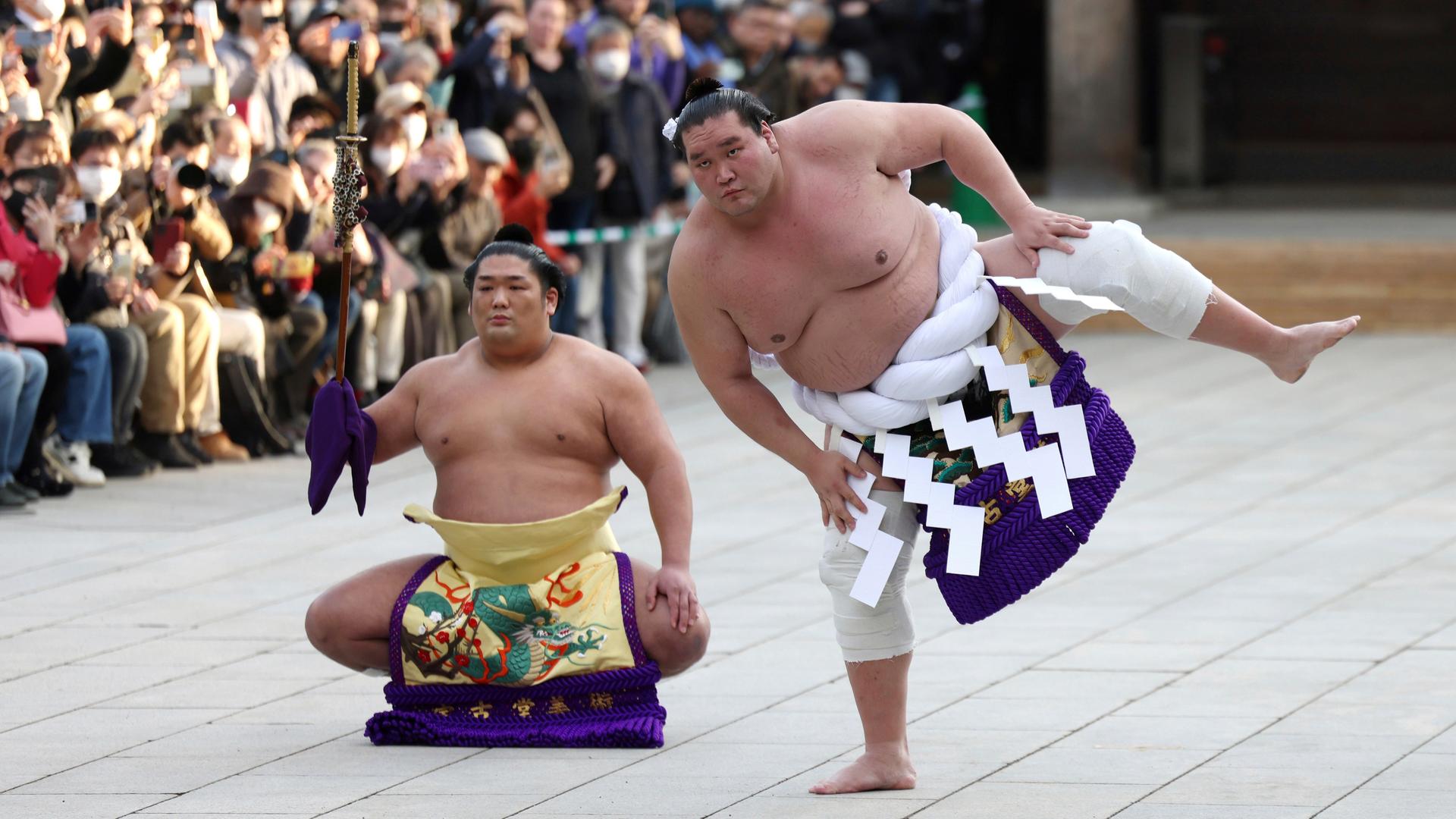 Der Sumo-Ringer Terunofuji (rechts) führt mit stampfenden Bewegungen in Ritual aus, daneben ein weiterer Ringer und Zuschauer im Meiji-Schrein in Tokyo. Der Sumo-Ringer Terunofuji (rechts) führt mit stampfenden Bewegungen in Ritual aus, daneben ein weiterer Ringer und Zuschauer im Meiji-Schrein in Tokyo.