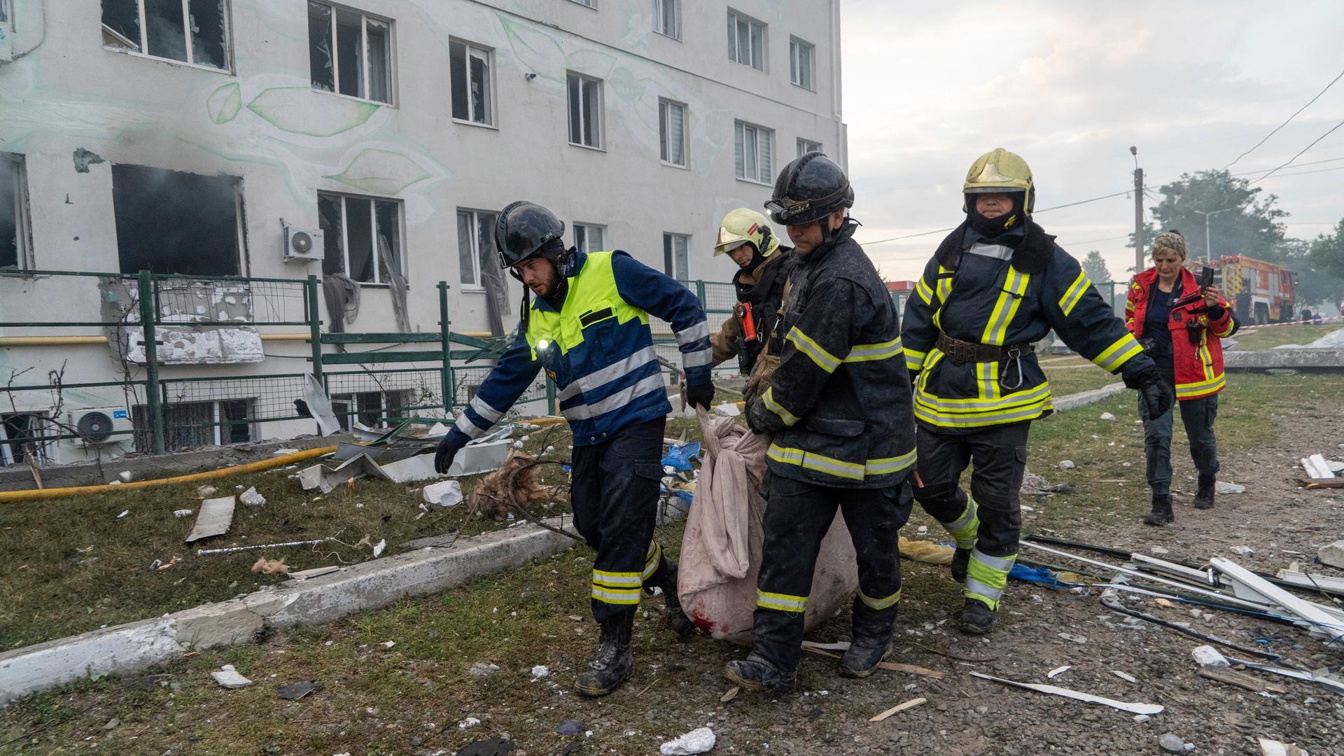 Rettungskräfte bergen einen getöteten Zivilisten nach einem Raketenangriff auf ein Wohngebäude in der ukrainischen Stadt Charkiv. 