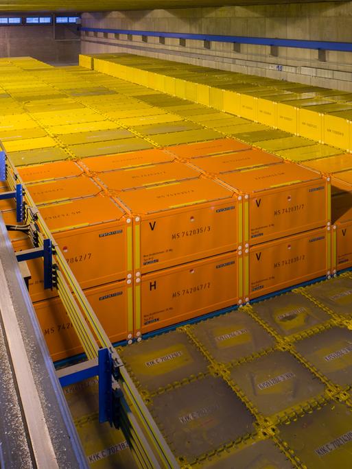Endlagerfähige Container mit radioaktivem Abfall stehen gestapelt in einer Halle.