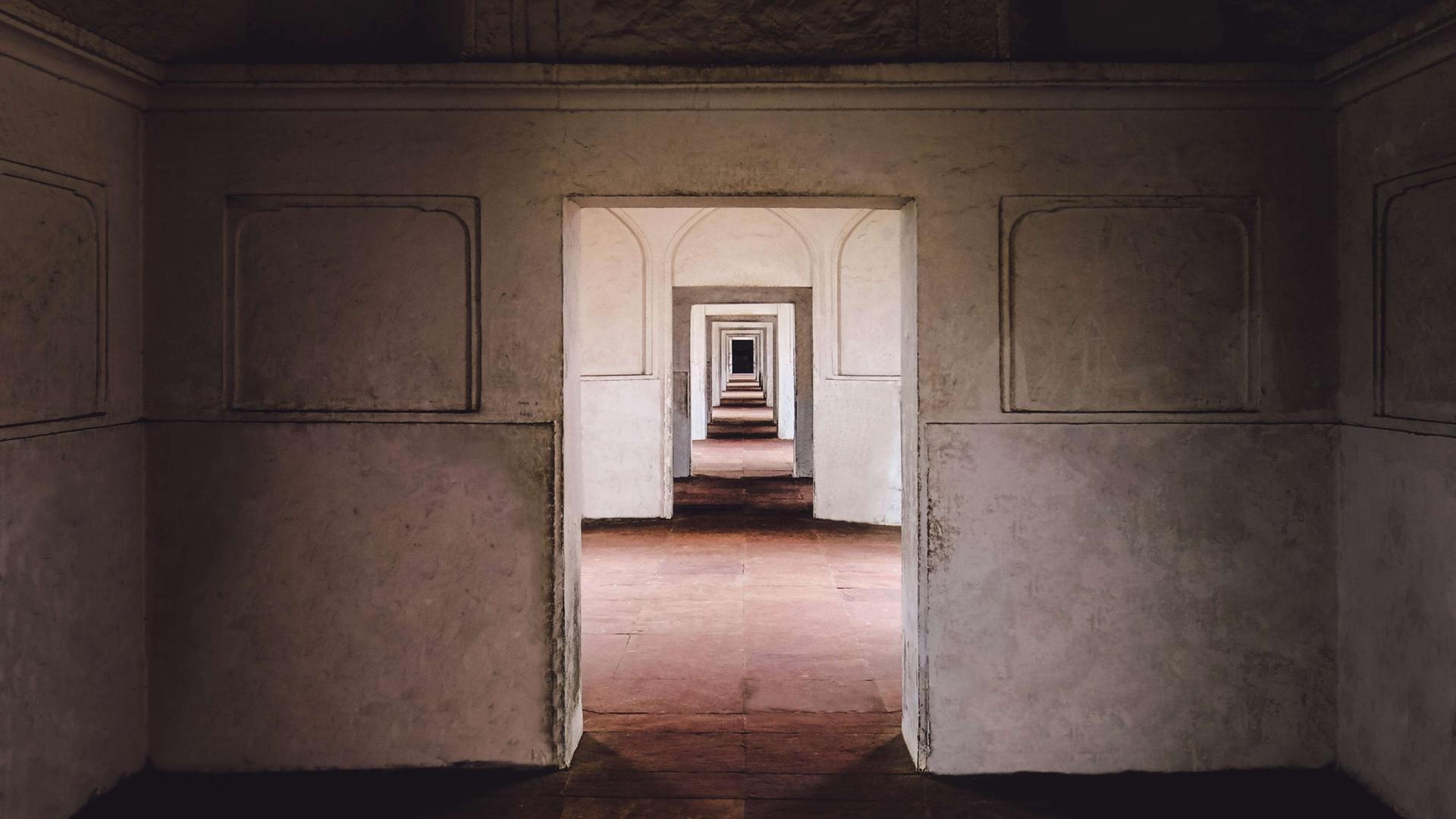 Ein leeres Gebäude in Lahore, Pakistan: Blick durch eine Tür, die zu einem leeren Raum mit Tür führt, die zu einem leeren Raum mit Tür führt, die zu einem leeren Raum mit Tür führt usw...