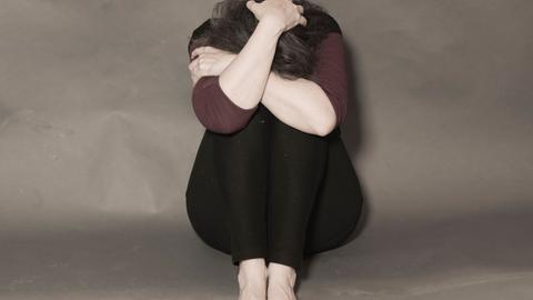 Eine Frau kauert mit nackten Füßen auf dem Boden