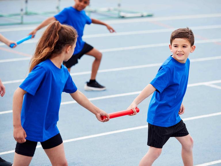 Kinder mit Staffelstab beim Team-Lauftraining Kinder mit Staffelstab beim Team-Lauftraining