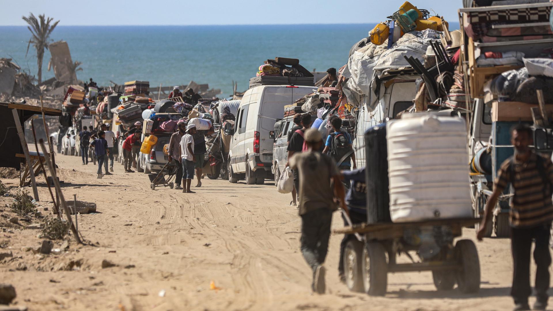 Das Foto zeigt eine lange Reihe von Menschen, die sich mit Autos, Karren und zu Fuß in eine Richtung bewegen. Die Menschen flüchten aus Gaza-Stadt.