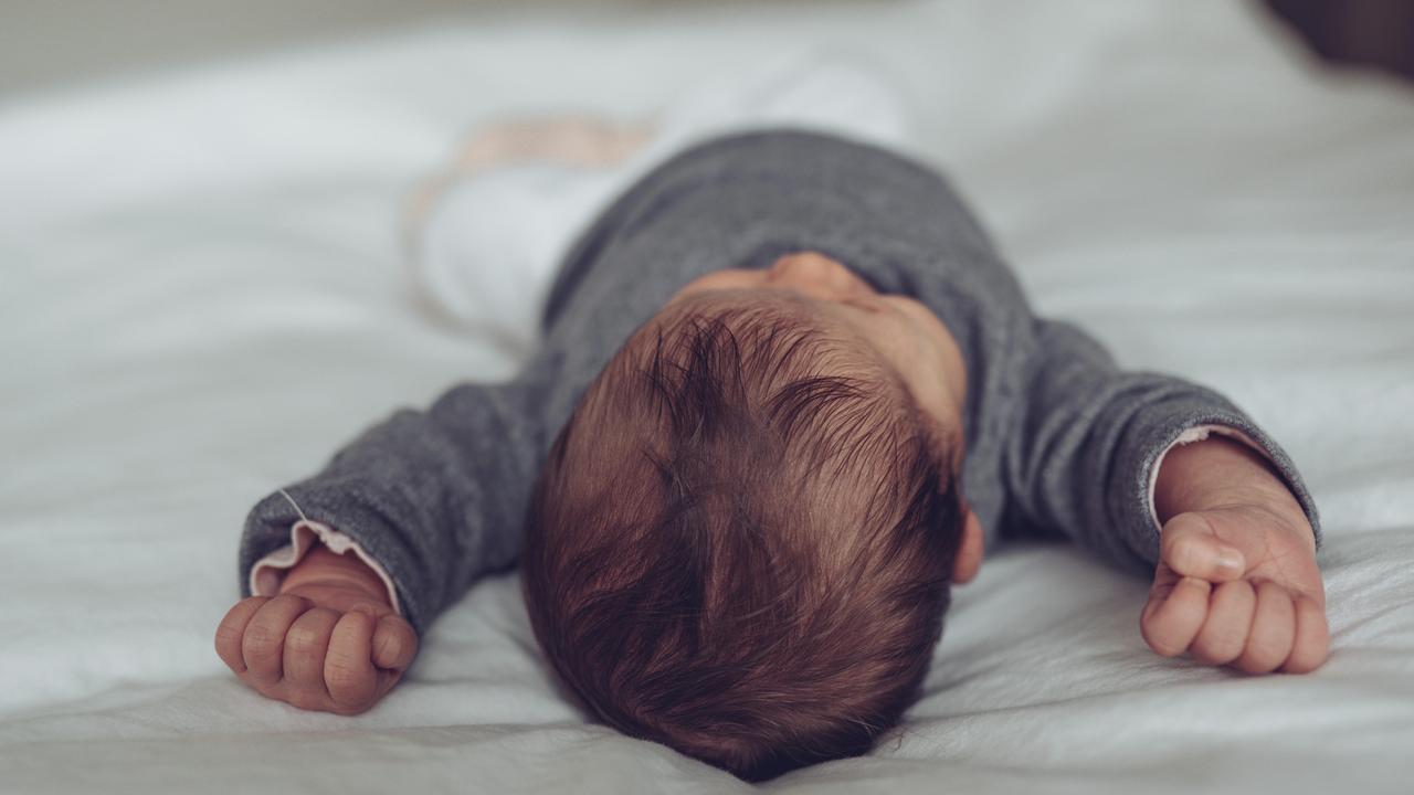 Schlafendes Baby liegt friedlich auf dem Bett