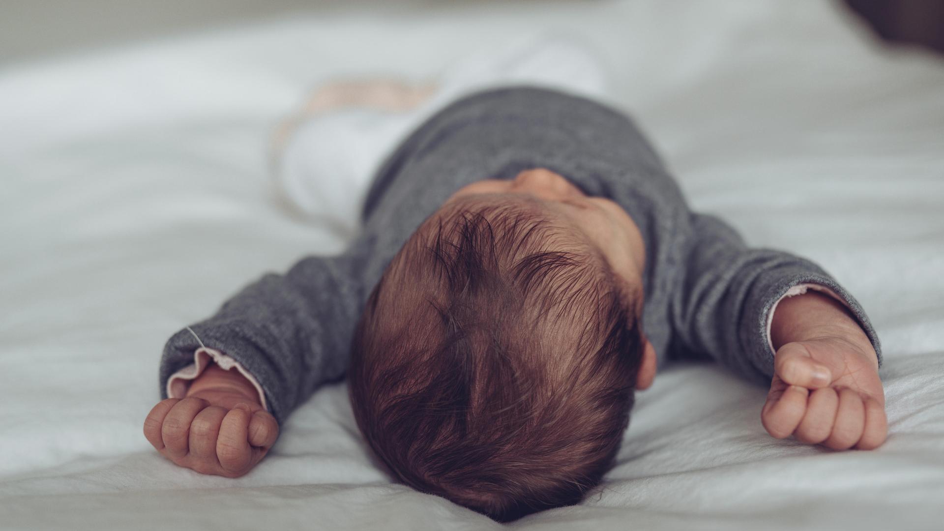 Schlafendes Baby liegt friedlich auf dem Bett