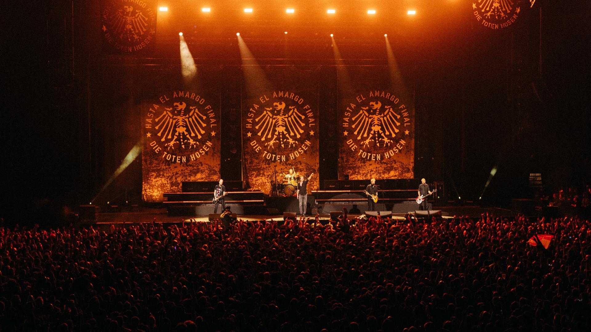 Das Abschiedskonzert der Toten Hosen in Argentinien in der Movistar Arena von Buenos Aires: Die Musiker stehen auf einer riesigen Bühne; im Vordergrund sind viele Zuschauer zu sehen.