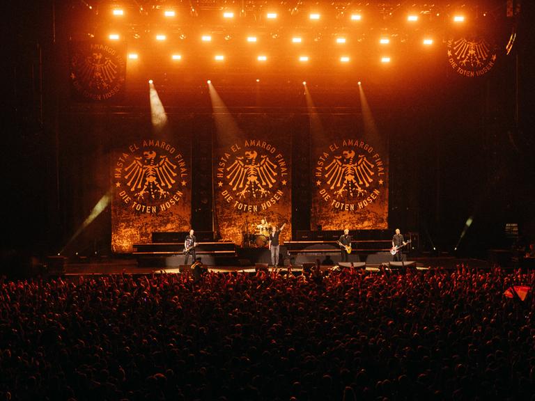 Das Abschiedskonzert der Toten Hosen in Argentinien in der Movistar Arena von Buenos Aires: Die Musiker stehen auf einer riesigen Bühne; im Vordergrund sind viele Zuschauer zu sehen.
