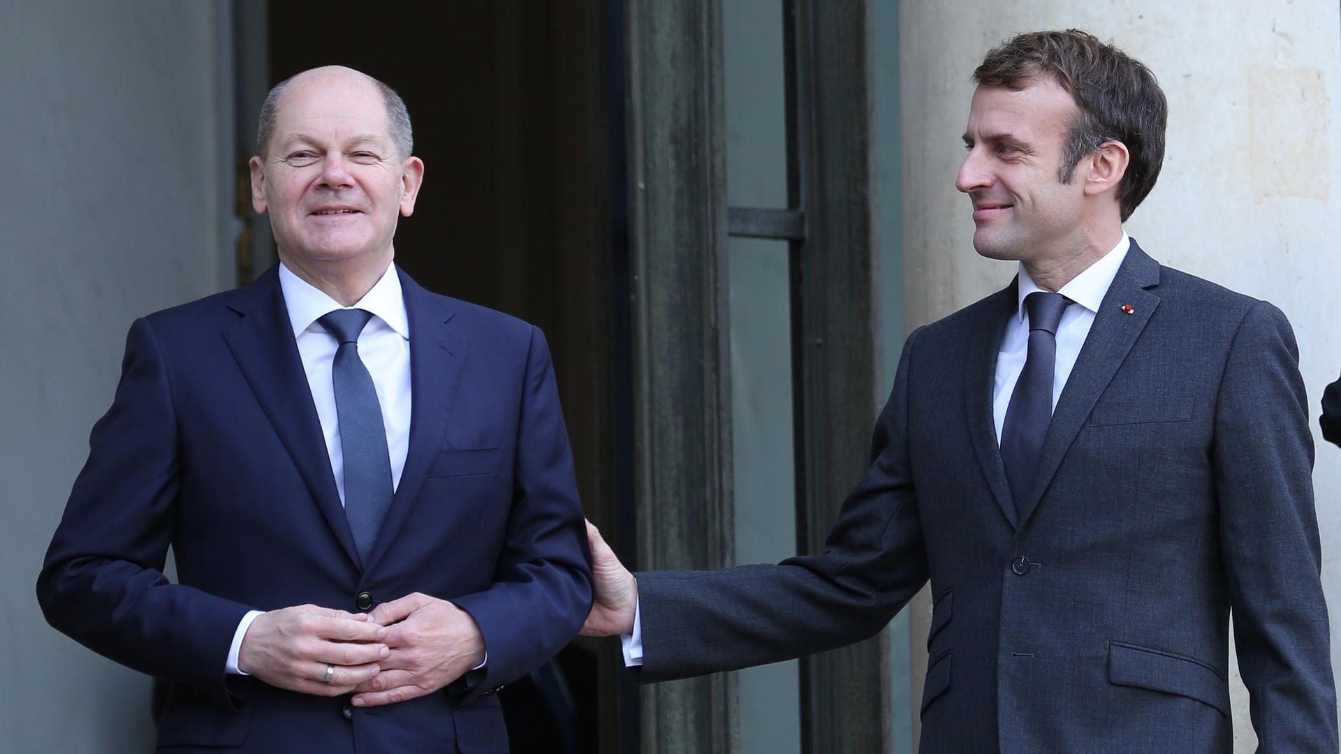 Der französische Präsident Emmanuel Macron (r) begrüßt Bundeskanzler Olaf Scholz bei seiner Ankunft Elysee Palast in Paris.